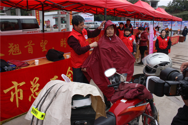 梧州市總工會(huì)的黨員義工們?cè)谑袞|出口春運(yùn)服務(wù)站助力“摩托大軍”平安返鄉(xiāng)，幫助他們檢查車輛和行李，穿上雨衣。--黃賀峰攝.j